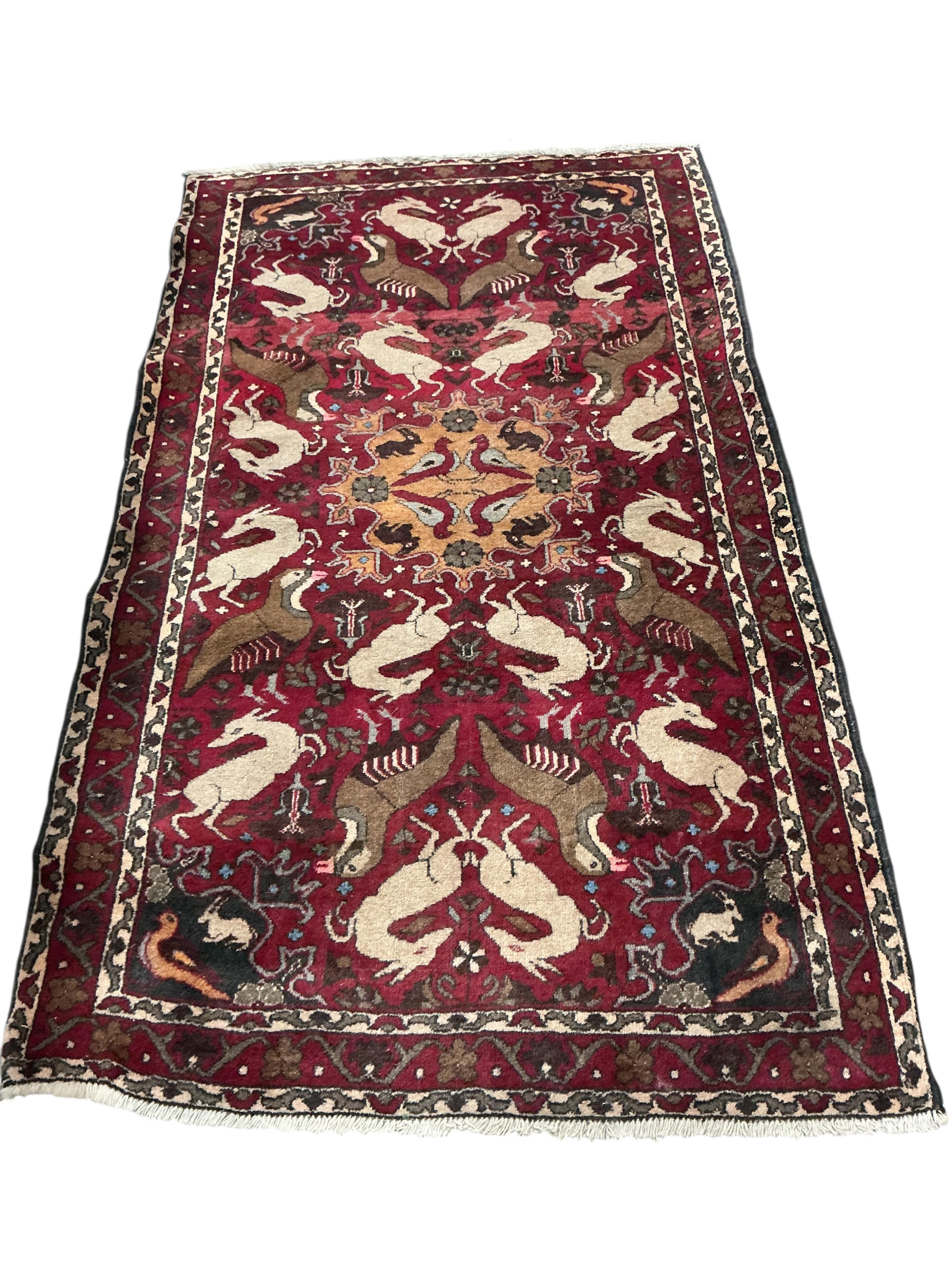A North West Persian red ground pictorial rug, 180 x 104cm